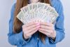 жінка в синій сорочці тримає гроші, гривні, купюри по 1000 грн