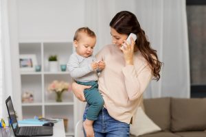 жінка тримає малу дитину на руках і говорить по телефону