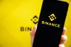 Смартфон з логотипом Binance на жовтому тлі