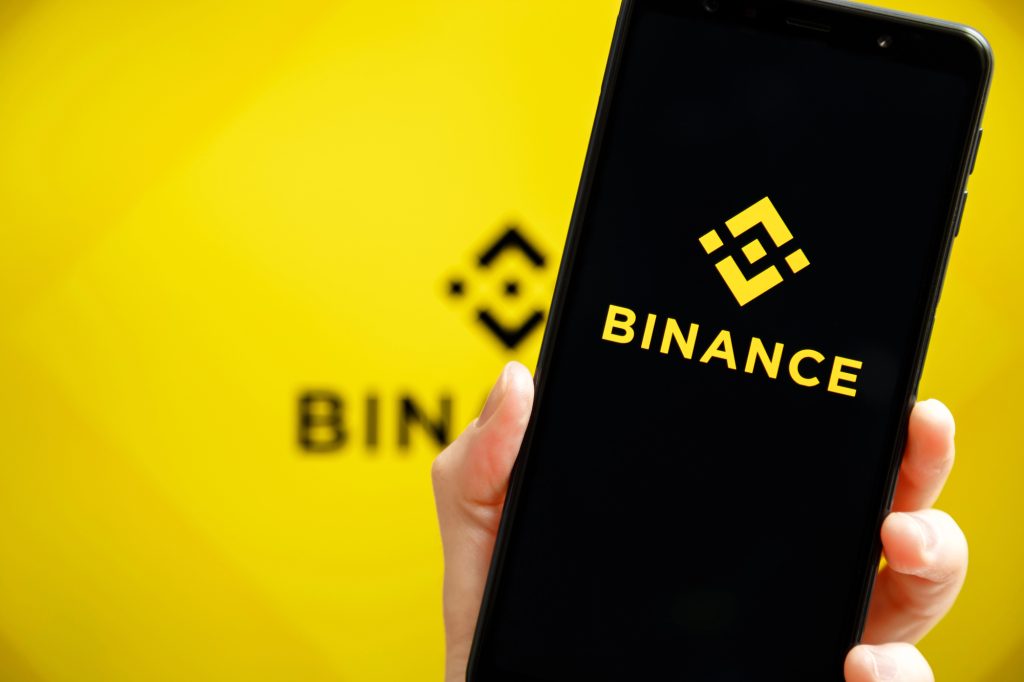 Смартфон з логотипом Binance на жовтому тлі