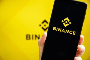 Смартфон з логотипом Binance на жовтому тлі